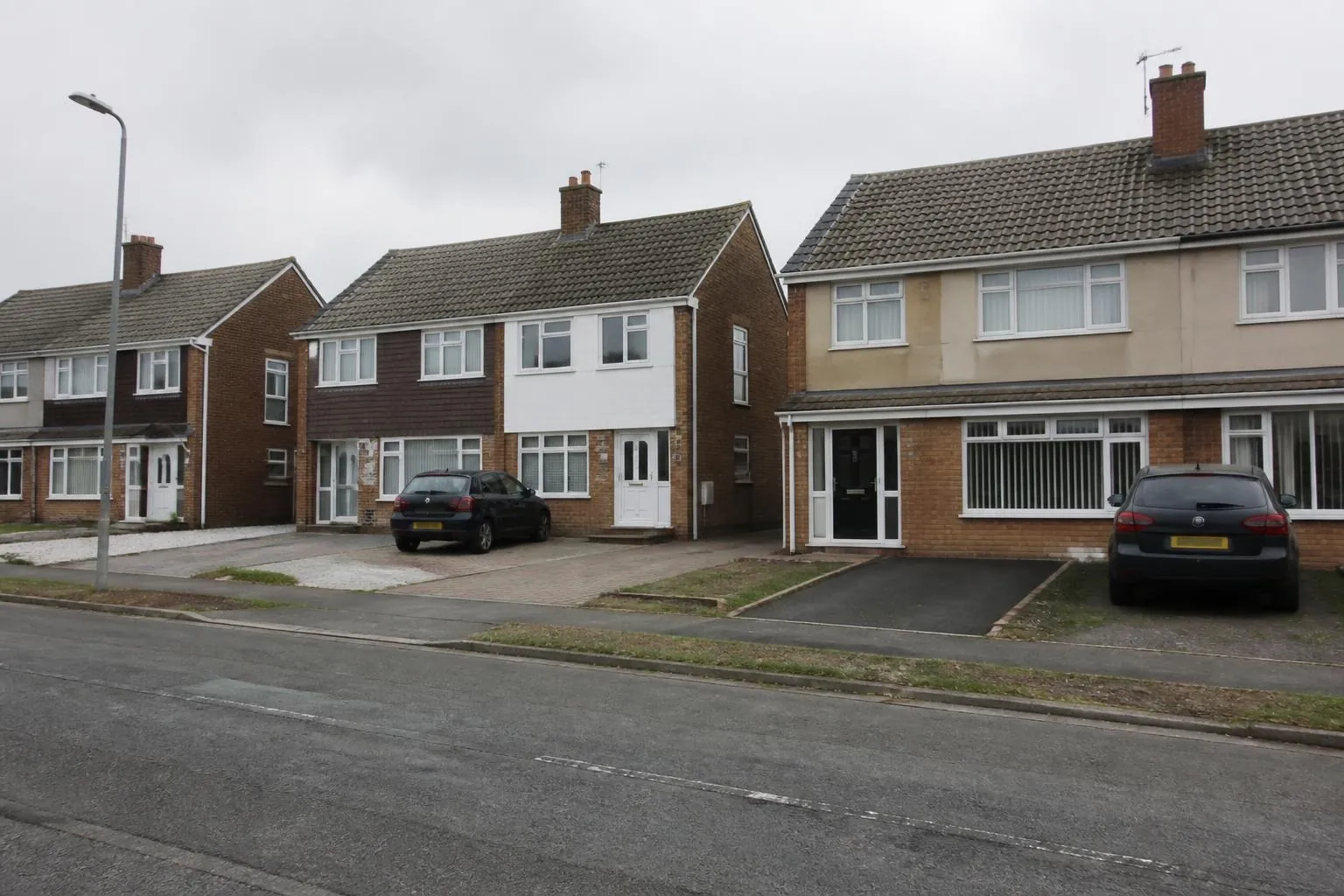 Street of brick semi-detached houses with different driveway surfaces