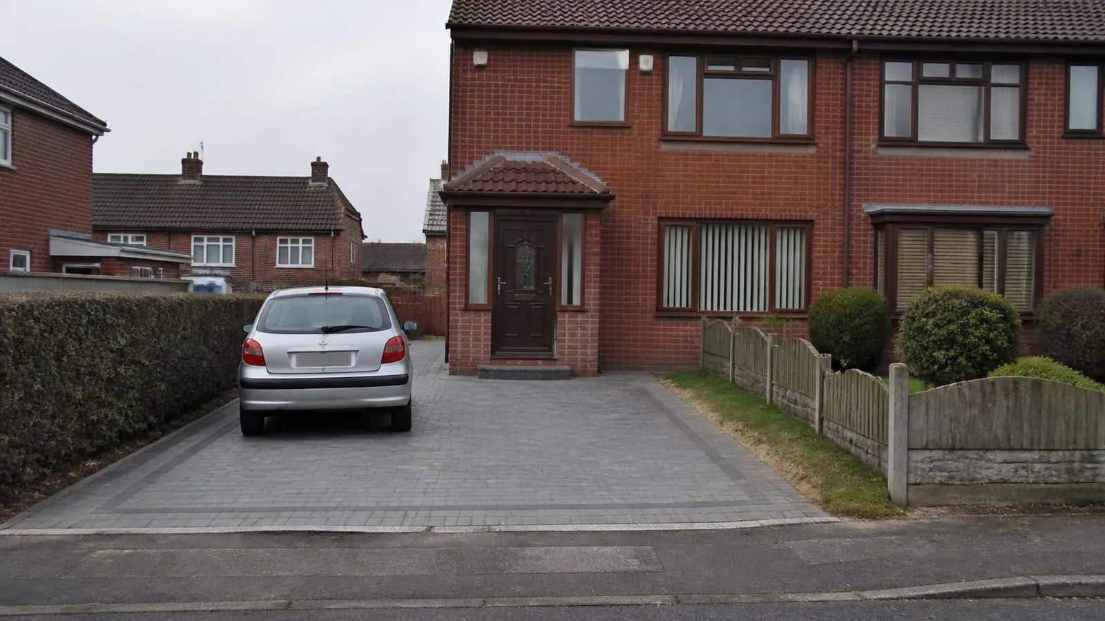 1980s red-brick semi with a porch and a grey block-paved driveway