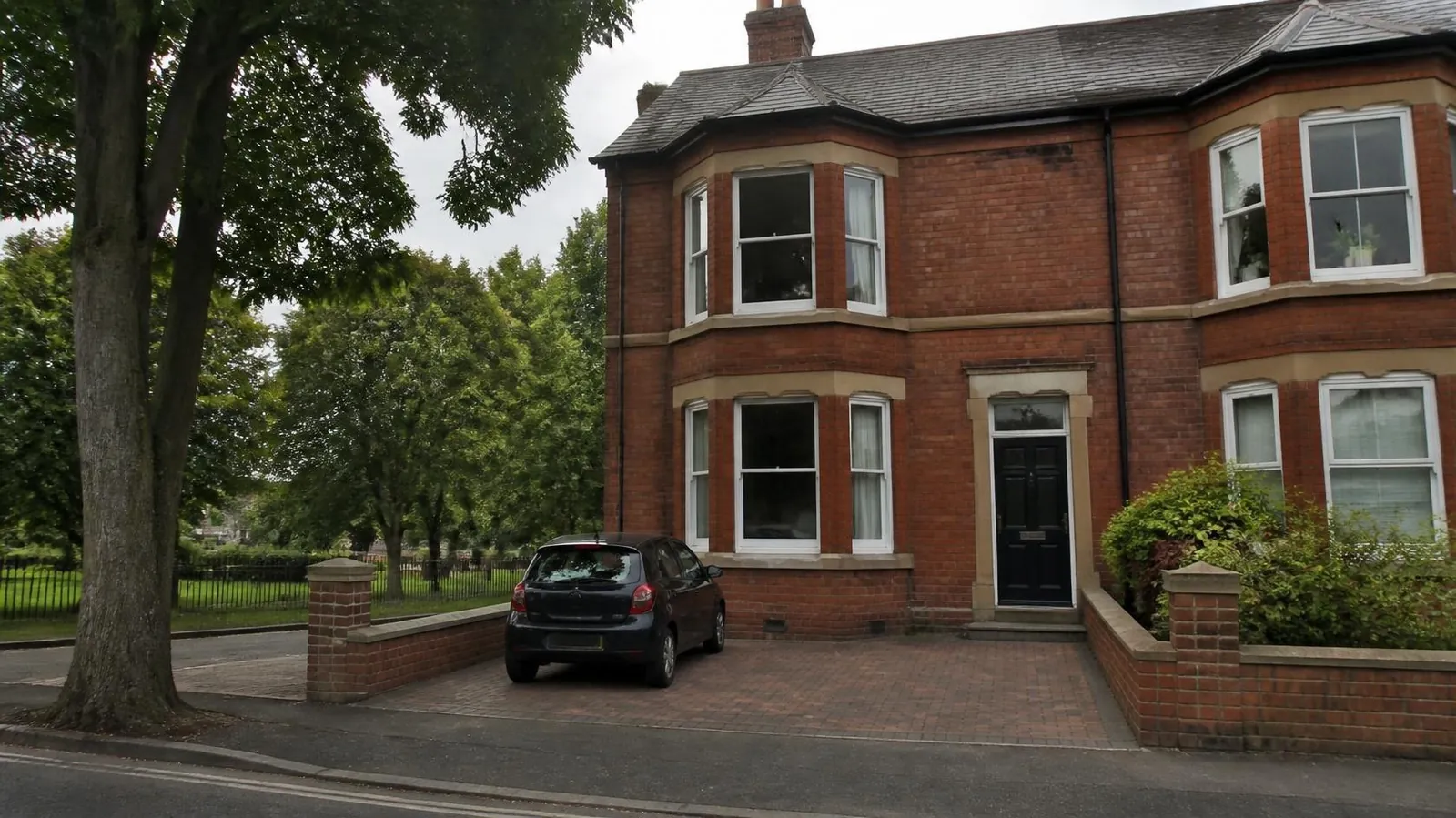 Victorian bay-fronted house with a small block-paved parking space between brick piers